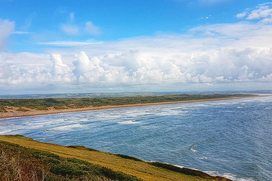 Spectacular view of a vast beach with rolling waves and a vibrant blue sky in summer, perfect for coastal holidays