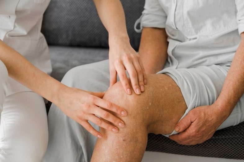 Physiotherapist assessing knee pain in an elderly patient for effective treatment and care