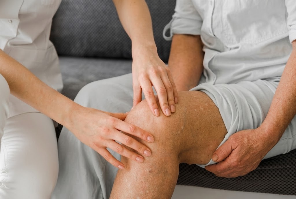 Physiotherapist assessing knee pain in an elderly patient for effective treatment and care