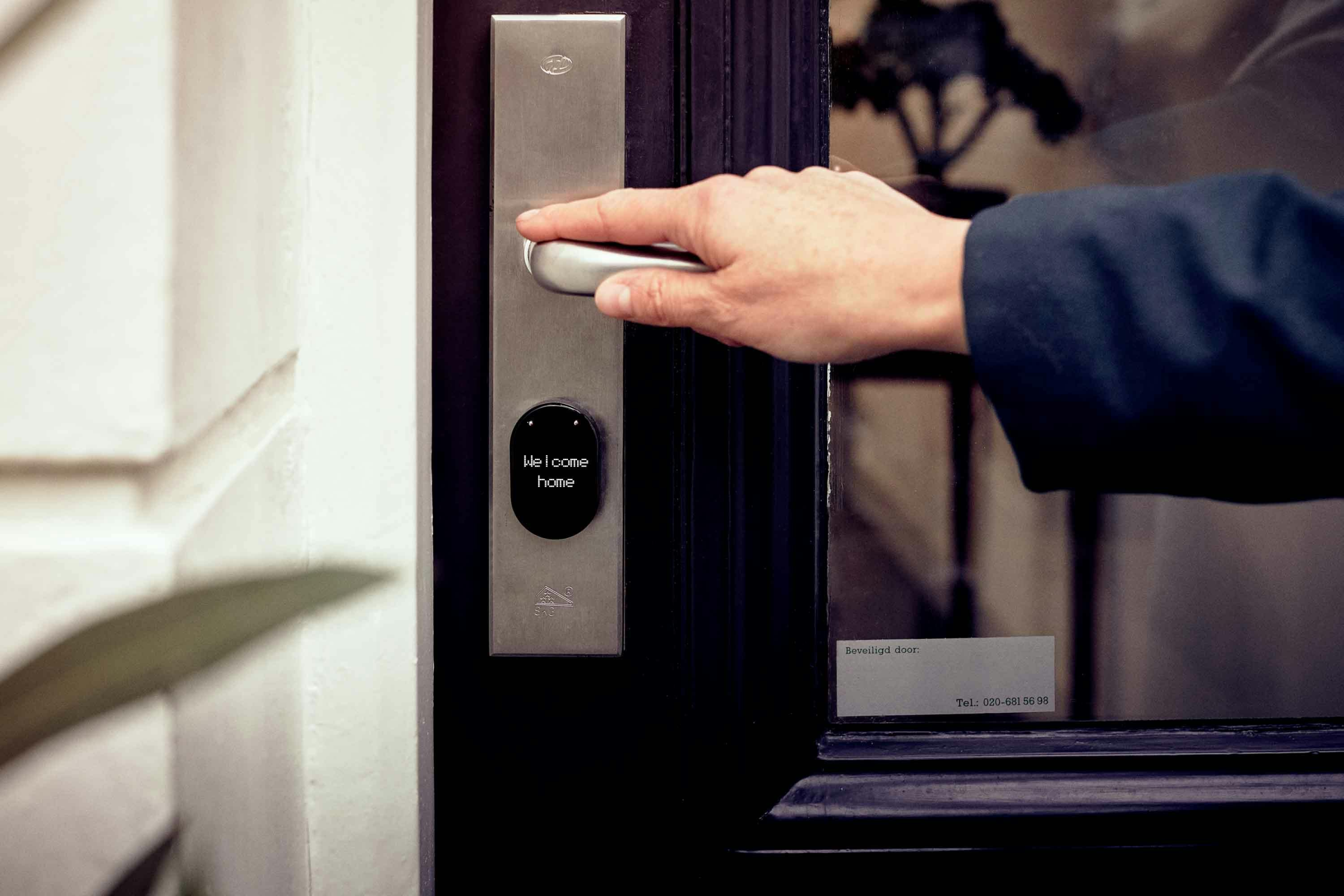 A person is opening a door by entering a code on a keypad mounted beside the door