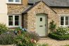 A quaint stone cottage featuring a green door and colorful flowers in the garden