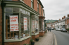 Shop with closing down sale signs on display in a quiet UK street, everything must go, last days for bargains