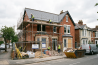 Construction work on a residential house with scaffolding, workers, and renovation materials on a quiet street in the UK